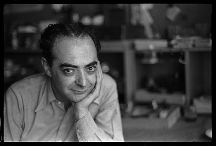 Fotografia em preto e branco de André Kertész, conhecido como Brassaï, capturando uma cena noturna de Paris em tons de cinza escuro e claro.