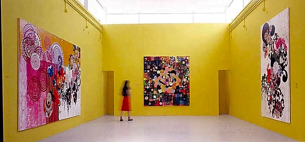 Pintura a óleo de uma mulher brasileira, Beatriz Milhazes, sentada em uma cadeira de madeira, com um sorriso suave e olhar introspectivo.