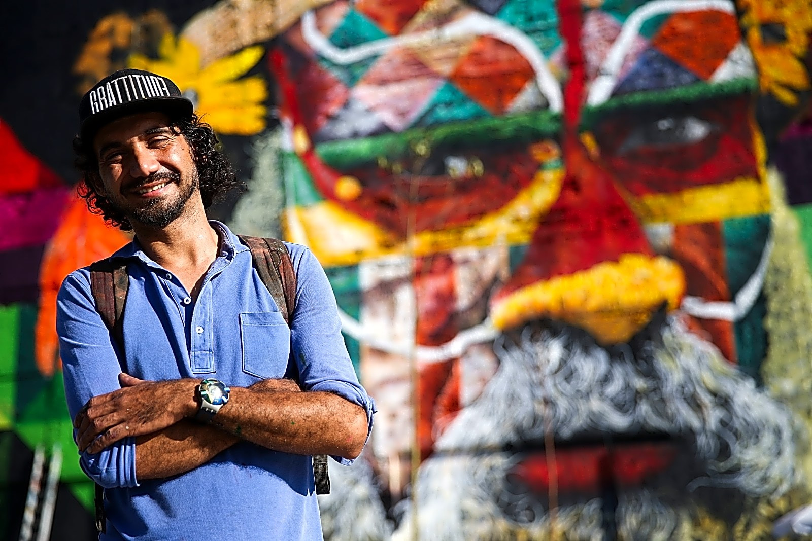 Pintura a óleo retratando Eduardo Kobra trabalhando em um mural urbano com cores vibrantes e detalhes realistas.