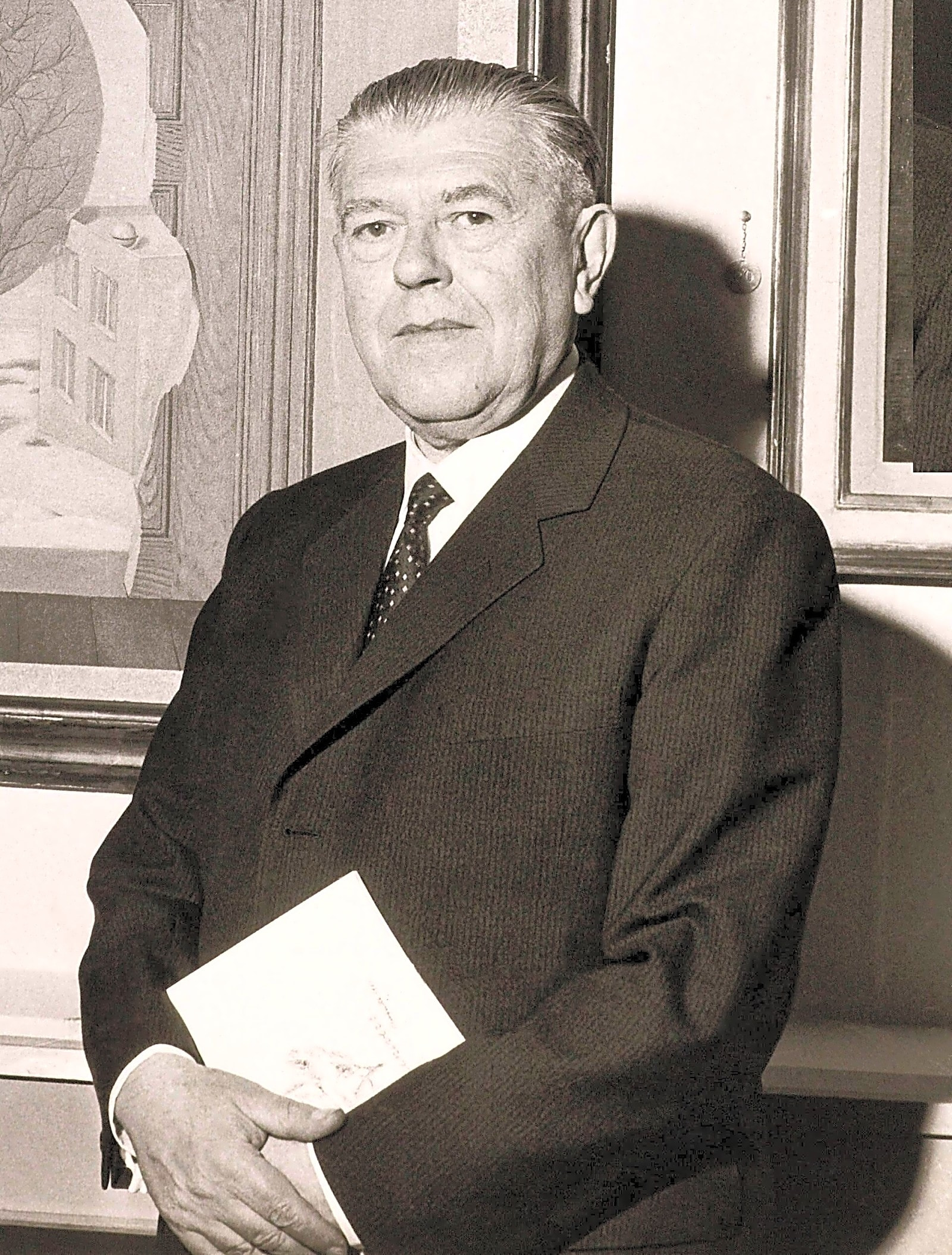 Pintura surrealista a óleo retratando René Magritte em frente a uma paisagem urbana cinzenta e monocromática.